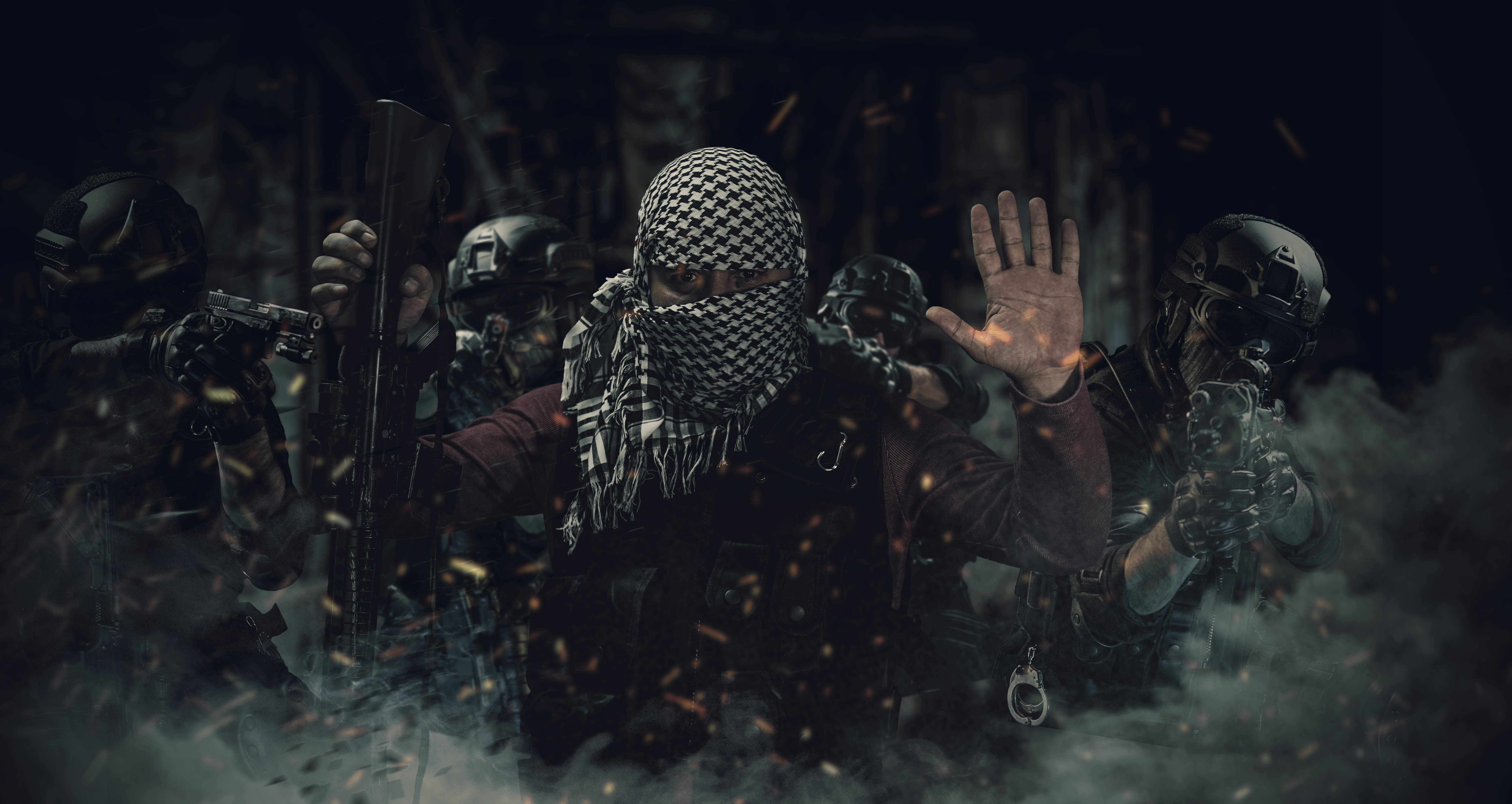 A picture that shows dressed actors. It looks like a terrorist that gives up surrounded by counter-terrorists.